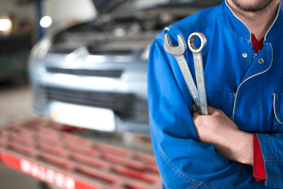 Cheezy stock photo of mechanic wearing coveralls and holding 2 big wrenches
