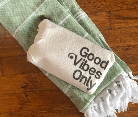 show your employees appreciation with personal gifts; image of sage green and white striped dish towel and folded white 'Good Vibes Only' dish towel on top