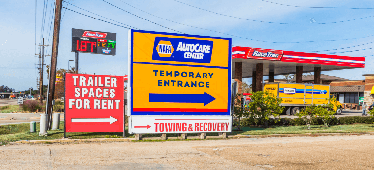 NAPA Auto Care Center "Temporary Entrance" sign with blue arrow directing customers where to go along side a Race Trac gas station