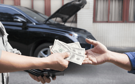 customer retention image showing male customer handing male mechanic hands money out of wallet with black car with hood open in background
