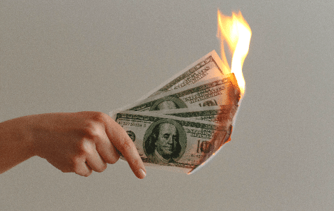 female hand holding 4 hundred dollar bills in flames
